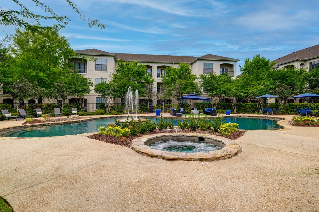 A large building with a pool and fountain in front.